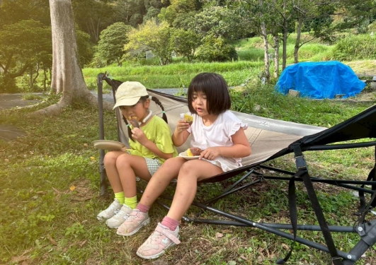 友達とハンモックでご飯を食べる女の子の写真