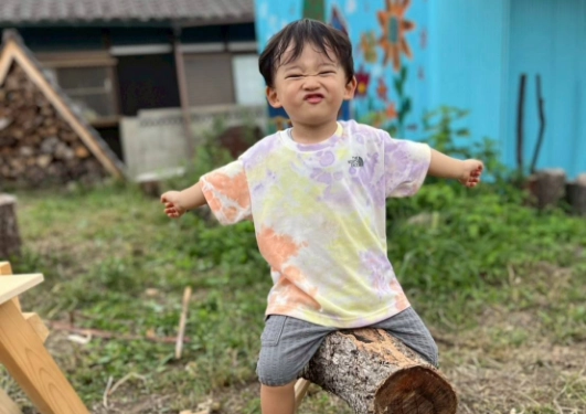 丸太のベンチに乗る子どもの写真